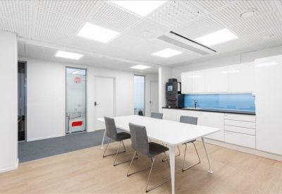 Modern kitchenette and dining area with sleek white cabinetry and blue backsplash.