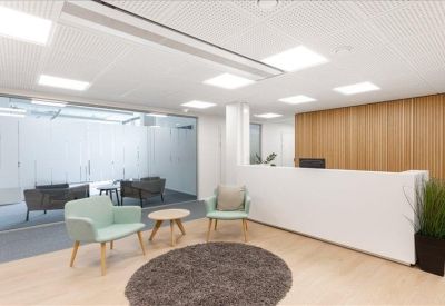 Minimalist reception area with a white desk and light blue armchairs.