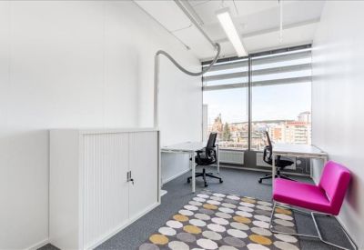 Bright private office featuring two desks and a vibrant pink armchair.