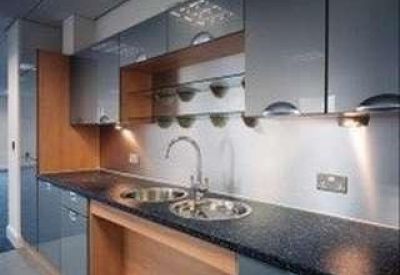 Modern communal kitchen with dark granite countertops and grey cabinetry.