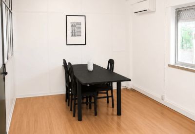 Simple meeting room with a long black table, four chairs, and minimalist wall art.
