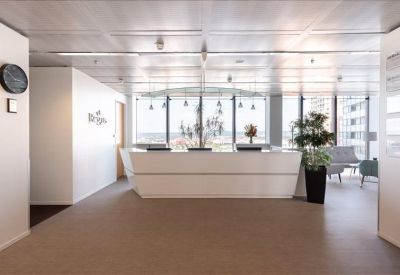 Sleek white reception desk with modern hanging lights and indoor greenery.