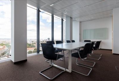 Long white conference table surrounded by black chairs in a sunlit meeting room.