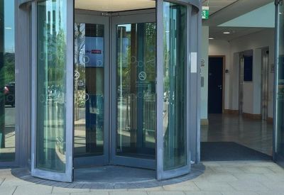 Close-up of the glass revolving door entrance under a metal canopy.