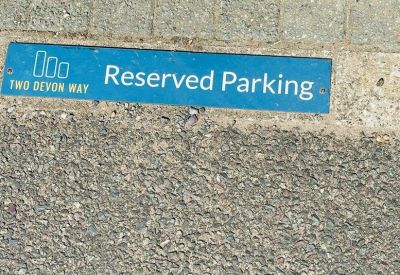 Reserved parking sign on the pavement featuring the building's logo.
