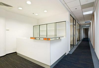 Modern white reception desk with minimalist cabinetry and a long carpeted corridor.