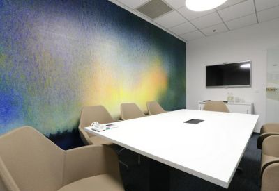 Conference room featuring a colorful abstract mural and stylish tan armchairs.
