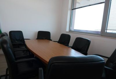 Professional meeting room with a wood-tone conference table and black leather chairs.
