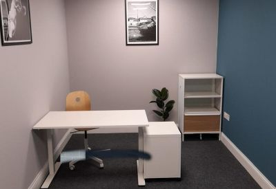 Private office featuring a white desk, blue accent wall, and framed wall art.