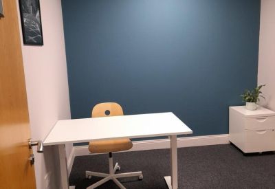 Bright workspace with a height-adjustable white desk against a teal feature wall.