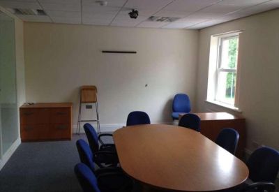 Professional meeting room featuring a large oval wooden table and blue chairs.