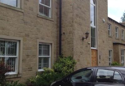 Facade of a stone-built office building featuring large windows and a black car parked in front.