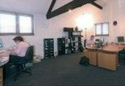 Large open-plan office space with multiple workstations and exposed wooden beams.
