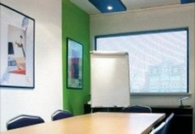 Modern conference room with a large wooden table, green feature wall, and natural light.