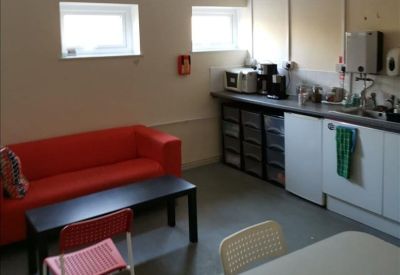 Communal breakout area with a red sofa, coffee station, and dining table.
