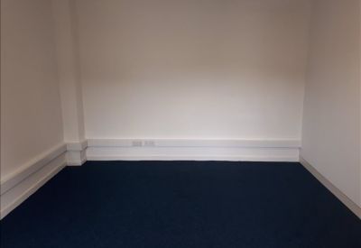 Small windowless office suite with white walls and dark carpeting.