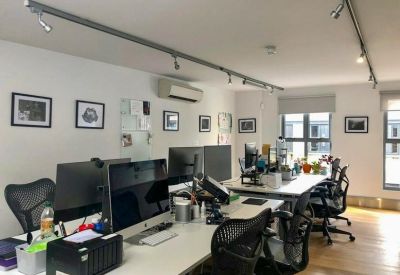 Professional open-plan workspace with multiple computer monitors, track lighting, and wooden floors.