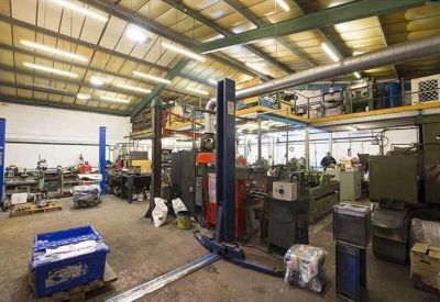 Spacious industrial workshop with mechanical lifts and various machinery.