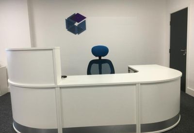 Clean white curved reception desk with a blue ergonomic chair and branded wall logo.