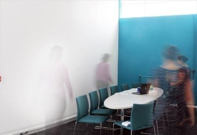 Meeting room featuring a large oval table, teal chairs, and a vibrant blue accent wall.