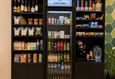 Branded grab-and-go market area with a snack shelf, beverage fridge, and coffee station.