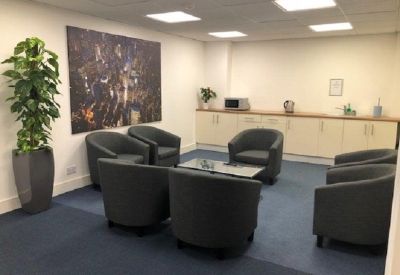 Communal breakout area with grey tub chairs and a large wall mural.