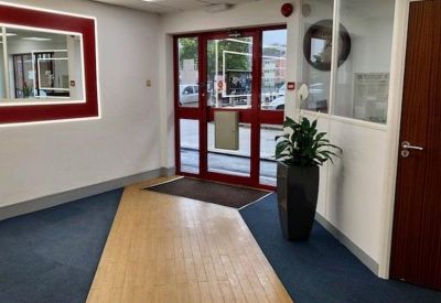 Reception entrance featuring red-framed doors and blue and wood-effect flooring.