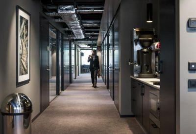 Modern office corridor featuring dark walls, sleek cabinetry, and integrated lighting.