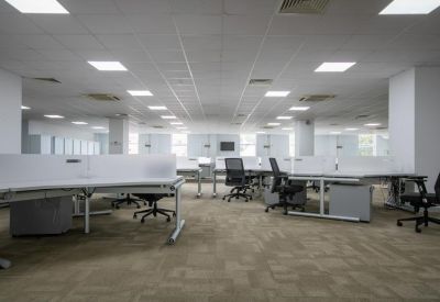 Large, modern workspace with rows of white desks and black chairs on neutral carpeting.