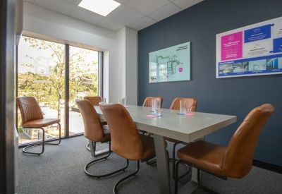 Professional meeting room featuring tan leather chairs and a white table next to a large window.