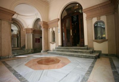 Grand building entrance featuring marble floors and arched stone doorways.