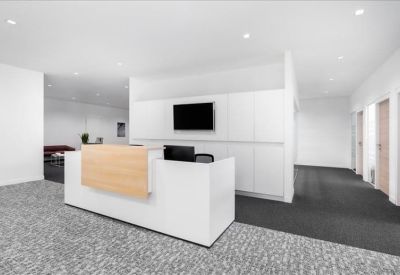 Minimalist reception area featuring a white and wood-fronted desk and a wall-mounted TV.