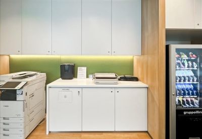 Functional printer and supply room with white cabinetry and a vending machine.