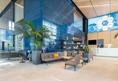 Spacious reception area with blue tiled walls, a large digital screen, and lounge seating.