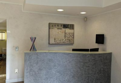 Modern reception desk with a textured grey facade and warm wood flooring.