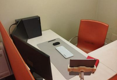 Corner workstation with an L-shaped desk, orange chair, and dual monitor setup.