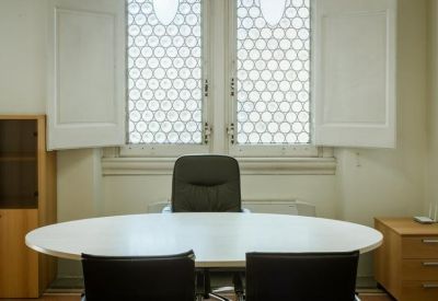 Bright conference room with a large white oval table and round patterned windows.
