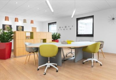 Spacious open-plan coworking area with a large oval table and colorful seating.