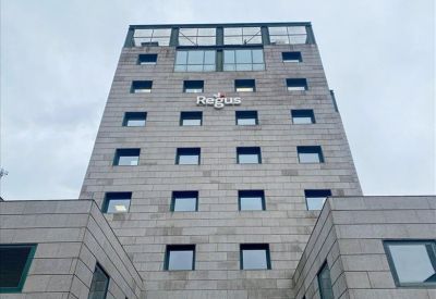 Bright boardroom featuring a long wooden table, ergonomic white chairs, and a red accent wall.