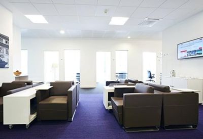 Lounge area with modular brown seating and blue carpeting under bright ceiling lights.
