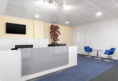 Modern reception area with a sleek grey desk, blue seating, and indoor plant.