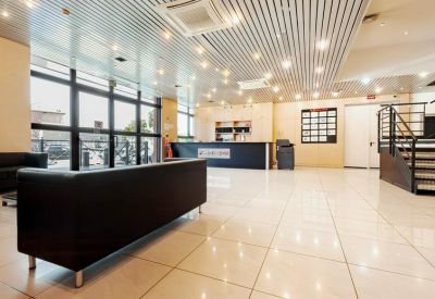 Bright reception area with a modern front desk, dark sofas, and polished tile flooring.