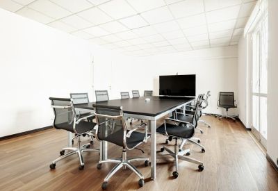 Sleek meeting room with a large black conference table and modern mesh office chairs.