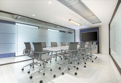 Spacious boardroom with a long white table and grey mesh chairs behind glass walls.
