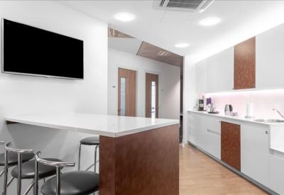 Modern breakroom with a white breakfast bar, stools, and wall-mounted television.