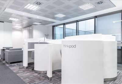 Semi-private white work pods with integrated desks in a bright office space.
