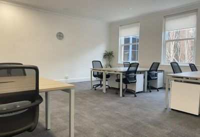 Bright four-person office suite with light wood desks and ergonomic mesh chairs.