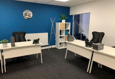 Small private office with a vibrant blue accent wall, desks, and white shelving.