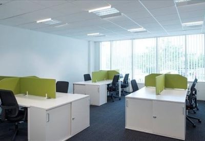 Bright open-plan workspace with white desks and green privacy screens.