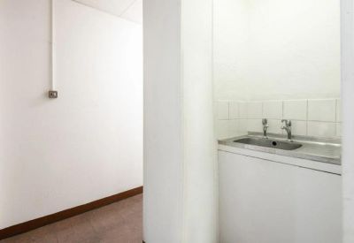Small kitchenette area with a stainless steel sink and white cabinetry.